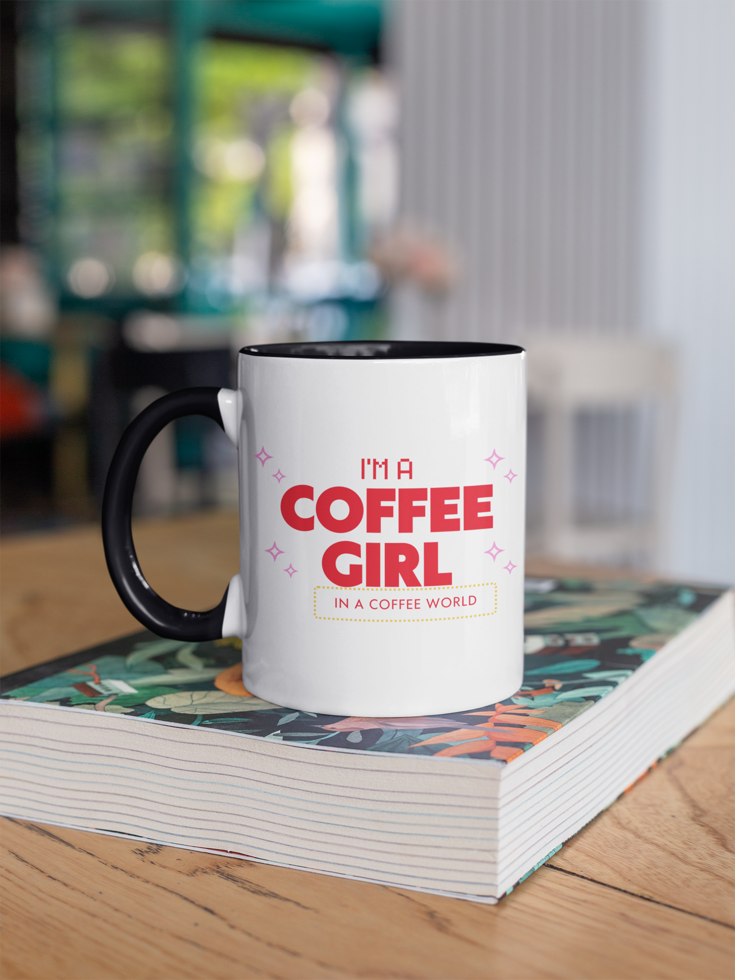 White mug with black handle featuring 'I'm a Coffee Girl in a Coffee World' text on a stack of books.
