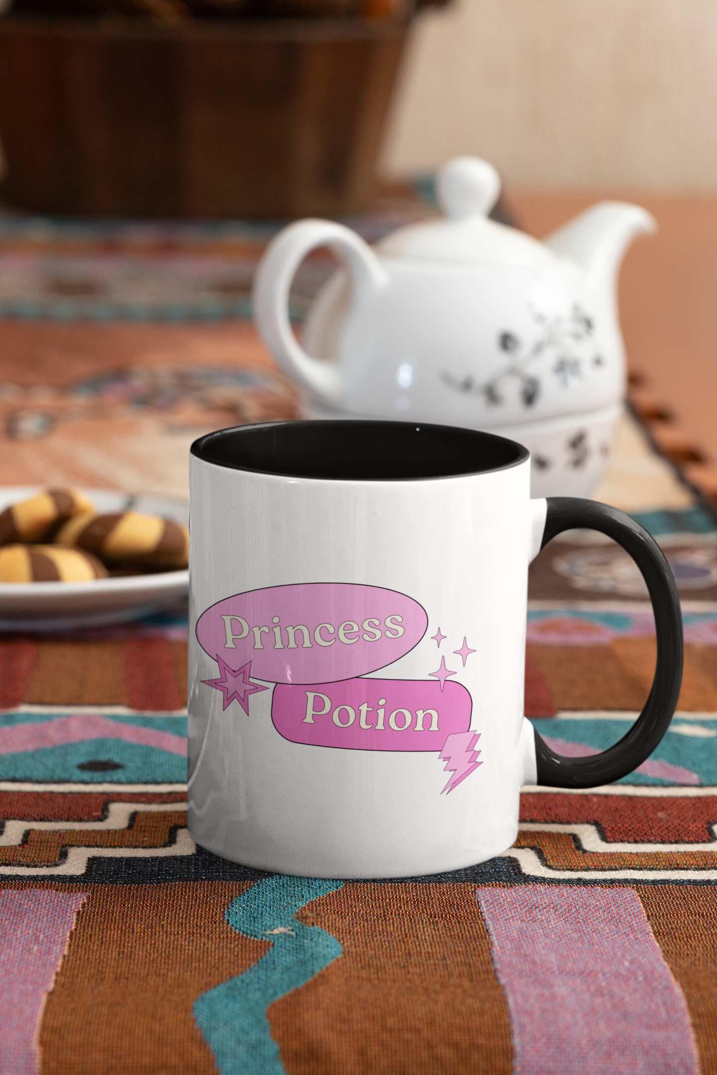 Mug with 'Princess Potion' design on a colorful tablecloth with a teapot in the background.